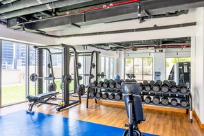 Un gimnasio con equipo de levantamiento de pesas, mancuernas y máquinas de ejercicio.