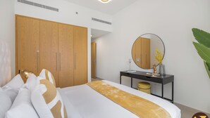 Una habitación de hotel con una cama grande, un armario, un escritorio con espejo y una planta.