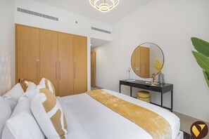 A hotel room with a large bed, a wardrobe, a desk with a mirror, and a plant. - Vogue, Downtown Bellevue Towers near Burj Khalifa and Dubai Mall (Dubai)