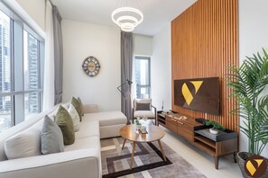 A modern living room with a sofa, coffee table, TV, and a large window. - Vogue, Downtown Bellevue Towers near Burj Khalifa and Dubai Mall (Dubai)