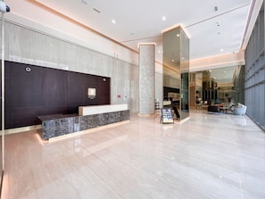 A modern reception area with a marble counter, a dark wall, and a glass partition.