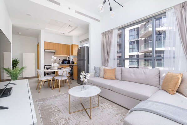 A modern living room with a sofa, a dining table, and a kitchen area.