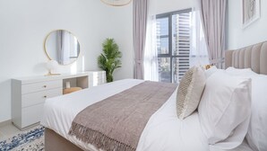 Ein Schlafzimmer mit Bett, Nachttisch, Spiegel und einem Fenster mit Vorhängen.