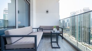 Un balcon avec un canapé, une petite table et une plante en pot.