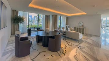 Un salon moderne avec une table ronde, des canapés et une grande fenêtre donnant sur la ville.