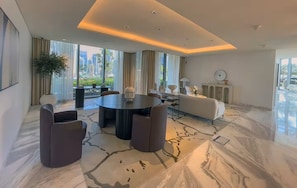A modern living room with a round table, sofas, and a large window with a city view.