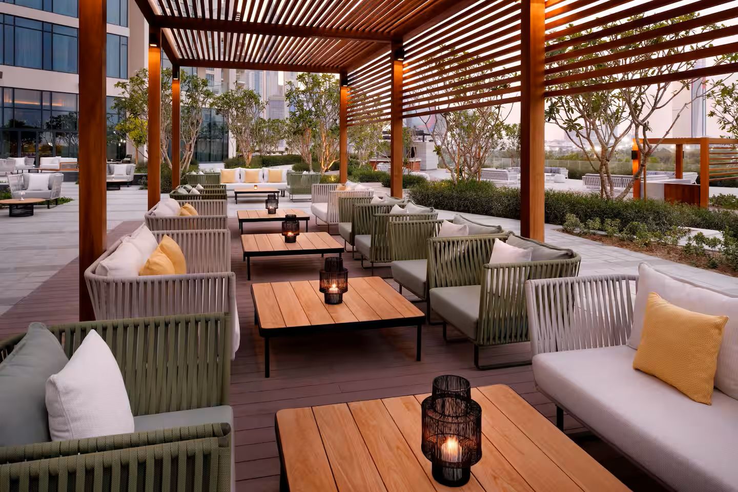 An outdoor seating area with wicker furniture, wooden tables, and candles.