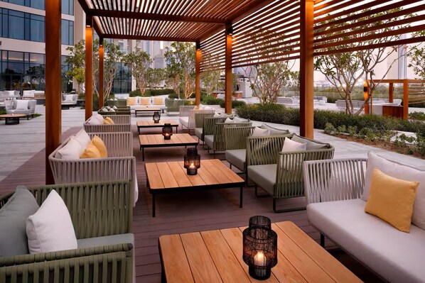 An outdoor seating area with wicker furniture, wooden tables, and candles.