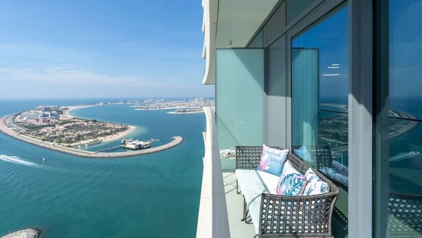 Ein Balkon mit Blick auf eine Küstenstadtlandschaft, darunter ein Yachthafen und eine kleine Insel.