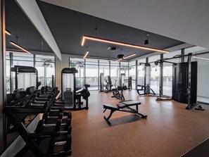 A modern gym with various exercise equipment, large windows, and a clean, spacious interior.