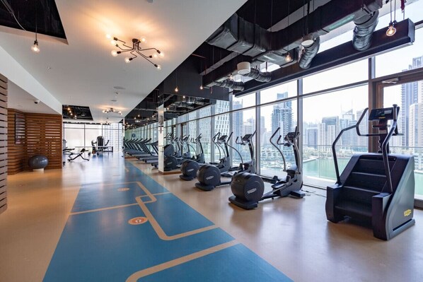 Un gimnasio con cintas de correr, bicicletas estáticas y pelotas de ejercicio.