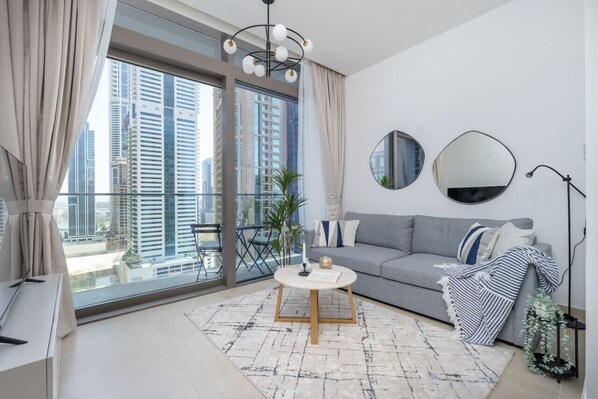 Una sala de estar moderna con un sofá gris, una mesa de centro redonda y un ventanal con vistas a la ciudad.