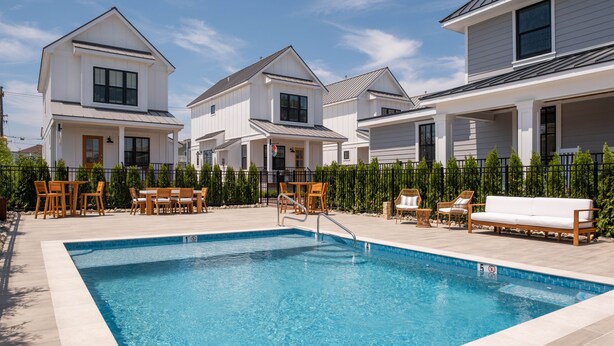 A swimming pool with a wooden deck, lounge chairs, and a fence. - The Hen Houses (Wildwood)