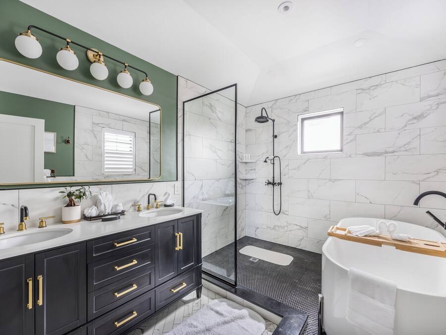 Een moderne badkamer met dubbele wastafels, een grote spiegel, een inloopdouche en een vrijstaand bad.