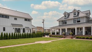 A residential area with two houses, a well-maintained lawn, and a clear sky. - The Hen Houses (Wildwood)
