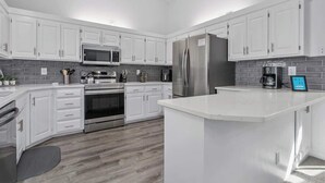 A modern kitchen with white cabinets, stainless steel appliances, and a large island.