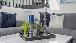 A modern living room with a grey sofa, a marble coffee table, and decorative items including candles and a lantern.