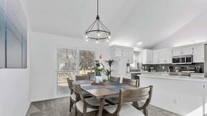 A modern kitchen with white cabinets, a central island, and a dining area with a wooden table and chairs.