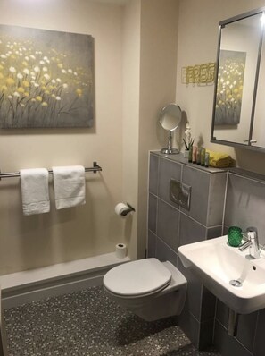 A bathroom with a toilet, sink, and a towel rack with two white towels.