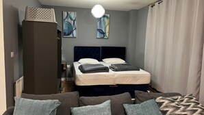 Un dormitorio con cama, armario, sofá y pinturas abstractas en la pared.