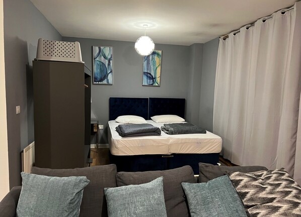 A bedroom with a bed, a wardrobe, a sofa, and abstract paintings on the wall.