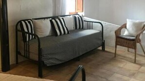 Ein gemütliches Zimmer mit einer Couch, einem Sessel und einem fenster mit Vorhängen.