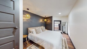 A bedroom with a bed, two pendant lights, a window with a view, a mirror, and a door. - King Beds|Parking|0.6 miles from UofL|Free WiFi (Louisville)