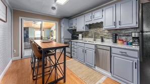 Una cocina moderna con armarios grises, una mesa de comedor de madera y un salpicadero de piedra.