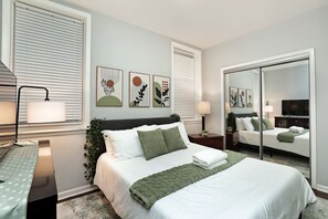 A modern bedroom with a bed, bedside tables, a mirror, and artwork on the walls. - Bridgeport Boho Chic Vibes (Chicago)