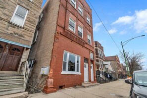 A multi-story brick building with a red facade, white windows, and a visible door. - Bridgeport Boho Chic Vibes (Chicago)