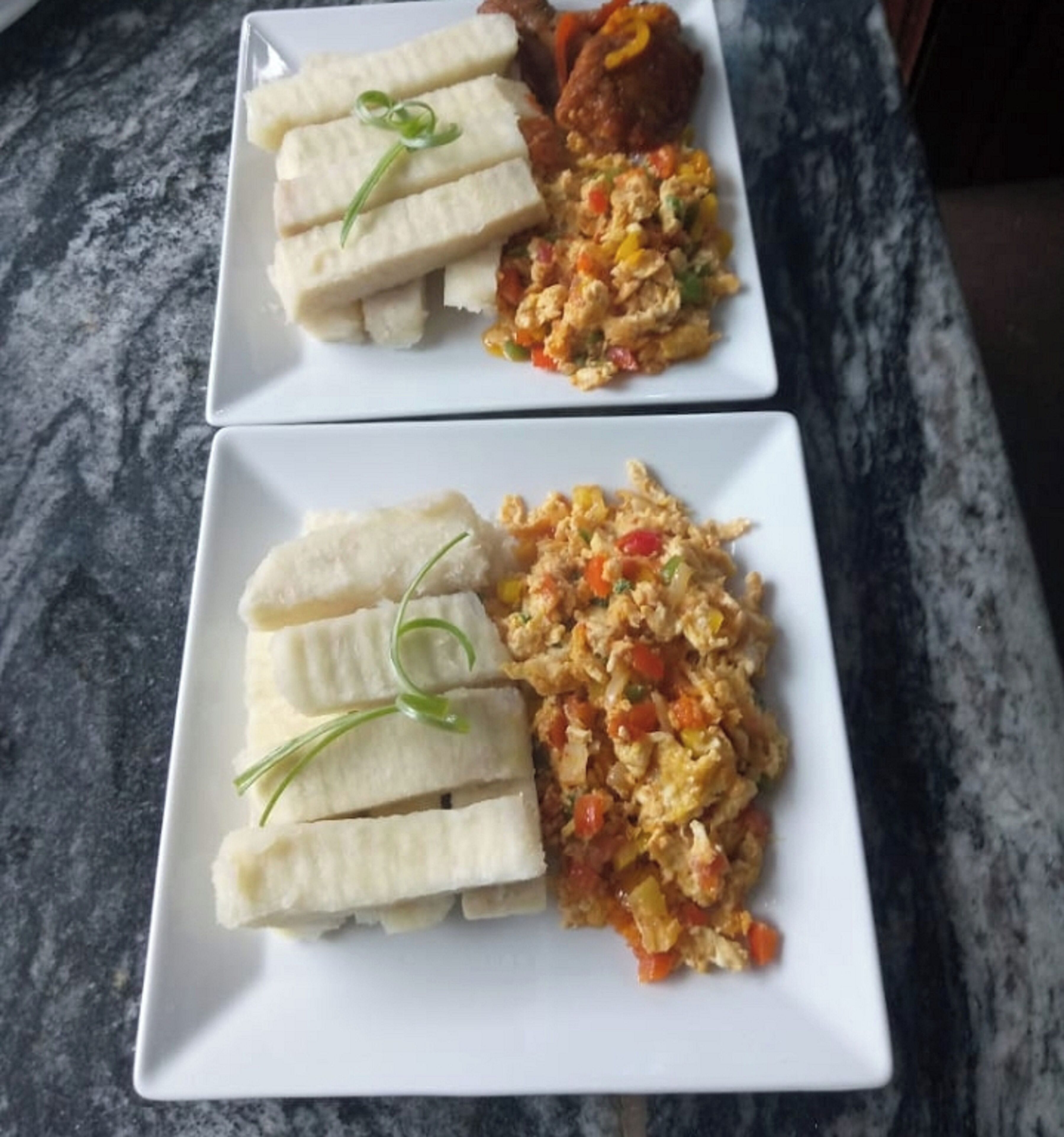 Two square plates with food on a marble countertop.