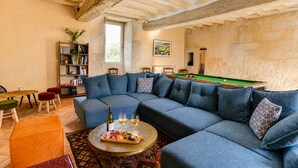Una sala de estar acogedora con un sofá modular, una mesa de billar y una estantería.