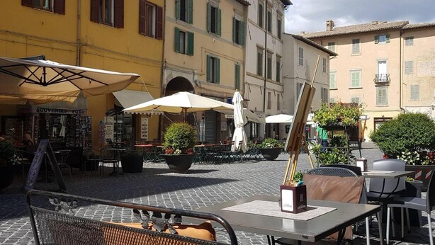 An outdoor café area with tables and chairs, umbrellas, and potted plants. - Sale! Beautiful 2-bed Apartment With Pool Access (Spoleto)