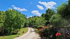 A gravel path leading through a garden with various plants and a metal fence on one side. - Sale! Beautiful 2-bed Apartment With Pool Access (Spoleto)