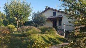 A house with a tiled roof, surrounded by lush greenery and a well-maintained lawn. - Sale! Beautiful 2-bed Apartment With Pool Access (Spoleto)