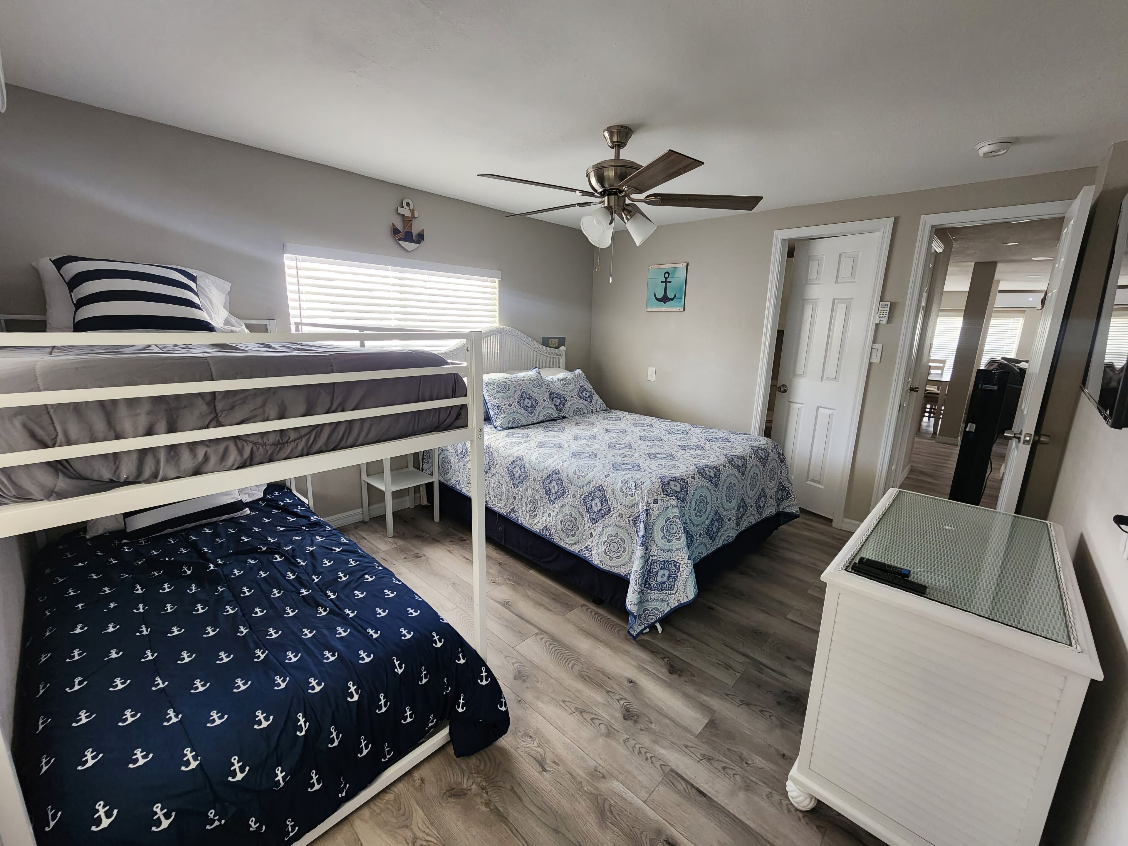 A bedroom with bunk beds, a ceiling fan, and a small white cabinet.