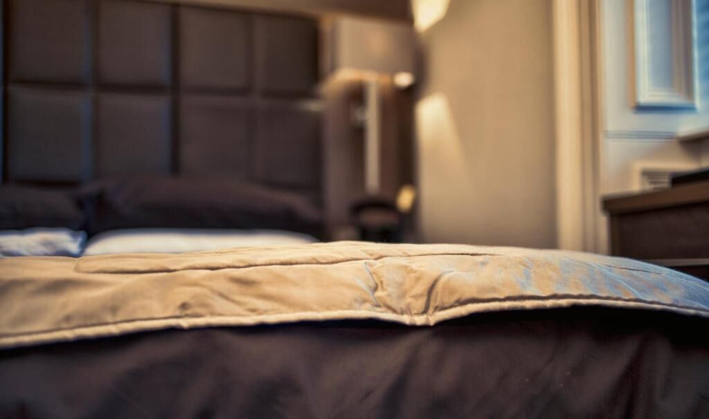A bed with a headboard, a bedside table, and a lamp.