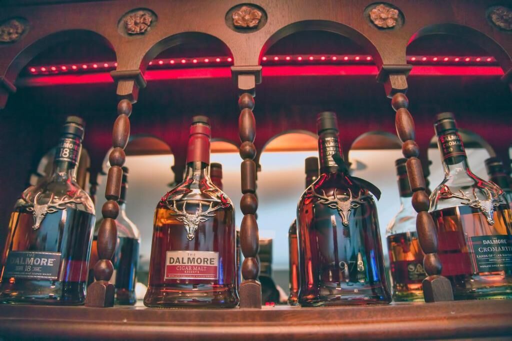 A bar with various bottles of liquor, including Dalmore Cigar Malt, arranged on wooden shelves.