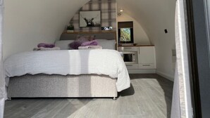 Un dormitorio con cama, una kitchenette pequeña y techo inclinado.