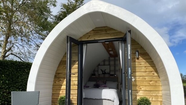 Un dormitorio acogedor, semiabierto, con interior de madera y arco exterior blanco.