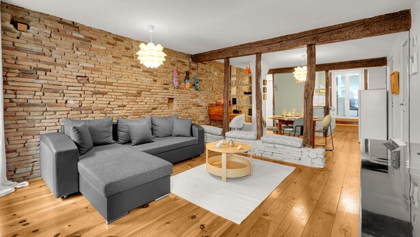 A modern living room with a sectional sofa, a round coffee table, and a brick wall. - Hippolyte - Appt avec terrasse couverte (Toulouse)