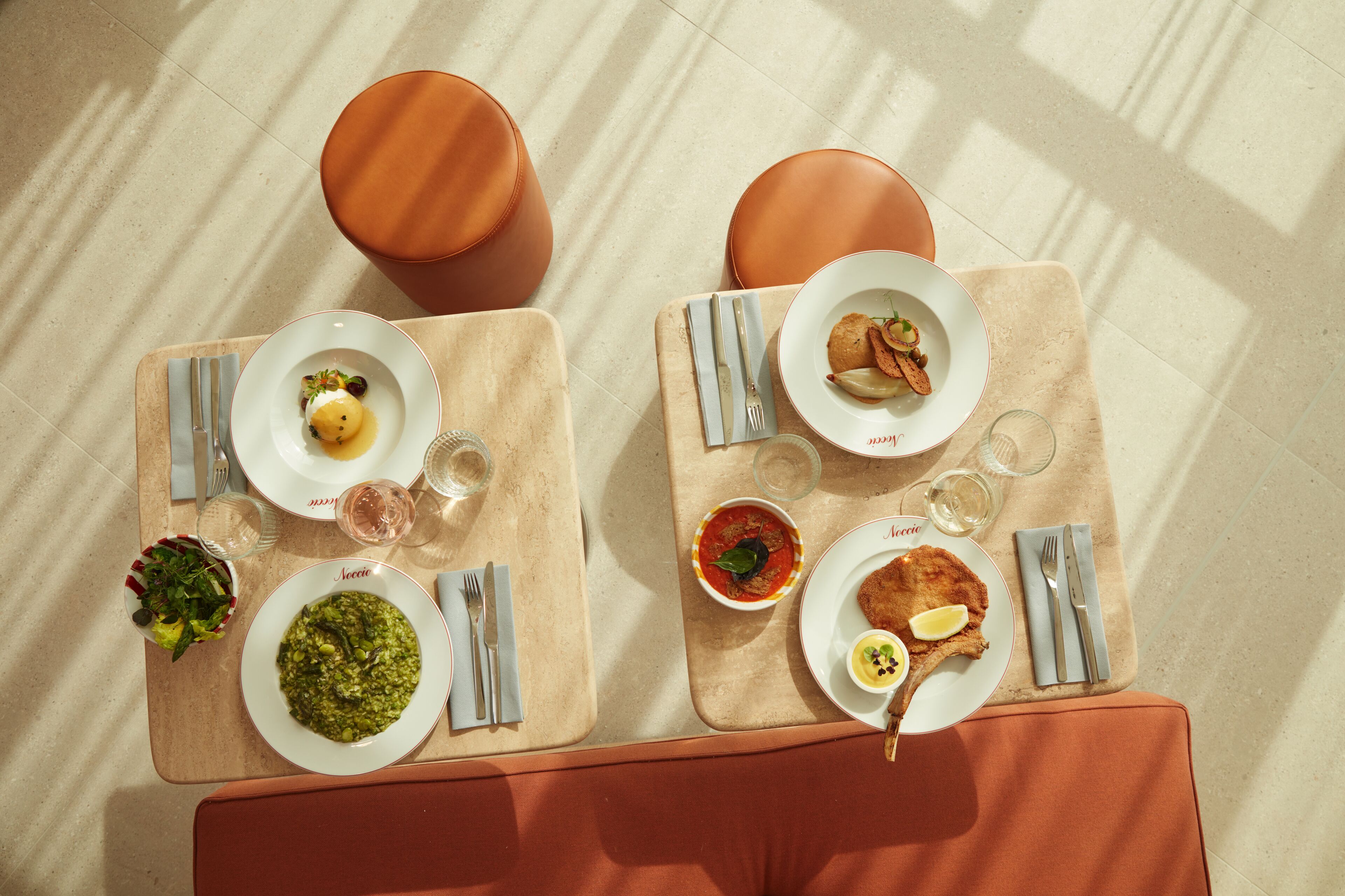 A dining table with two plates of food, cutlery, and glasses.