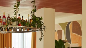 Eine Bar mit Holztresen, Hockstühlen und einer Auswahl an Flaschen.