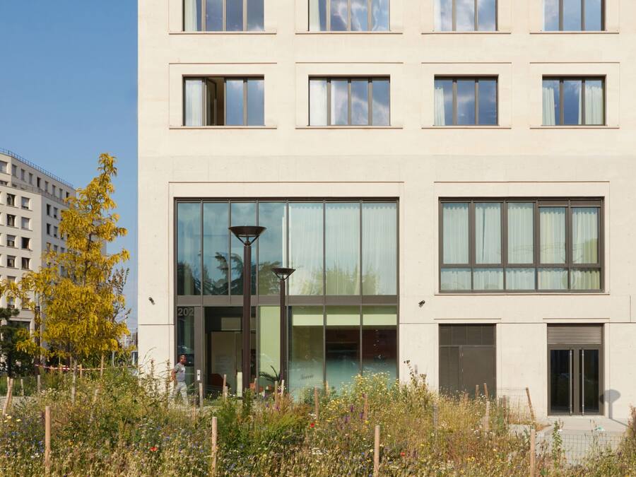 Ein mehrstöckiges Gebäude im modernen Architekturstil, mit einer Reihe von Fenstern und einem großen Glastür-Eingang.
