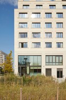 Un edificio de varias plantas con un estilo arquitectónico moderno, que presenta una serie de ventanas y una entrada de vidrio amplia.