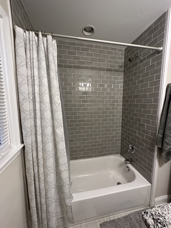 A bathroom with a shower, a bathtub, and a tiled wall. - Convenient Charlotte Comfort (Charlotte)