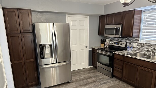 A modern kitchen with stainless steel appliances, dark wooden cabinets, and a granite countertop. - Modern 3BR 2BA West Enid (Enid)