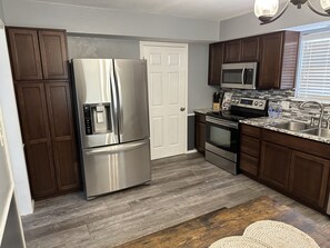Una cocina moderna con electrodomésticos de acero inoxidable, armarios de madera oscura y encimera de granito.