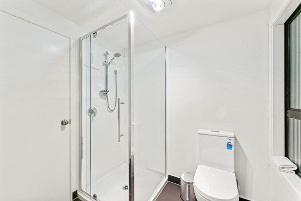 Une salle de bain moderne avec une douche à parois de verre, des toilettes et un lavabo.