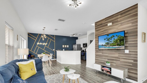 Un salon moderne avec un canapé bleu, une table basse et un téléviseur fixé à un mur en bois.
